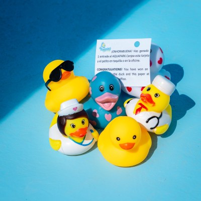 Six rubber ducks with different designs and a card on a light blue background.