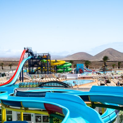 Colorful water park with slides and pools, desert hills in background.