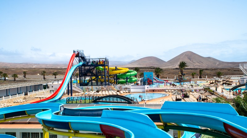 Colorful water park with slides and pools, desert hills in background.