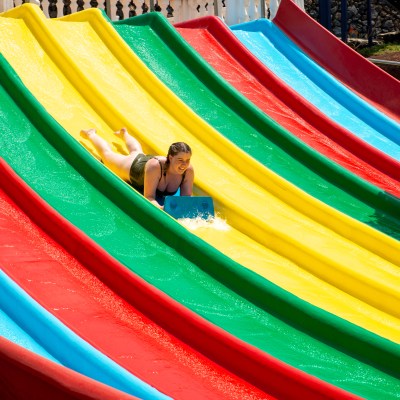 Person sliding down colorful multi-lane water slide on a sunny day.