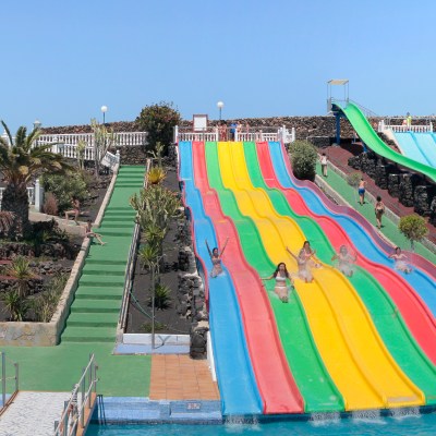Multiple colorful water slides at an outdoor water park on a sunny day.