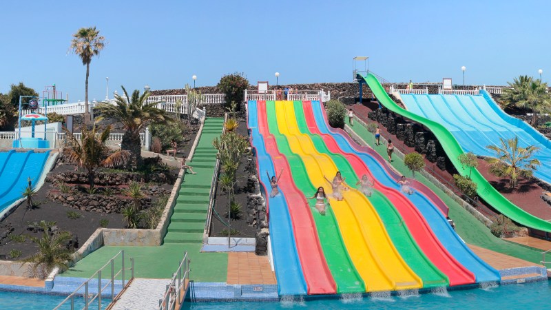Multiple colorful water slides at an outdoor water park on a sunny day.