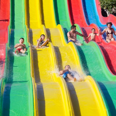 People sliding down colorful water slides at a water park.