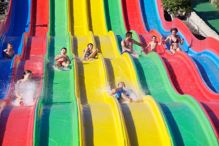 People sliding down colorful water slides at a water park.