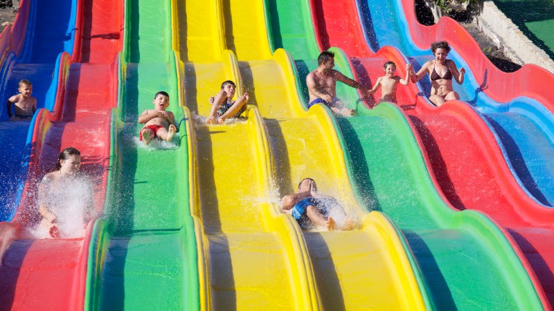 People sliding down colorful water slides at a water park.