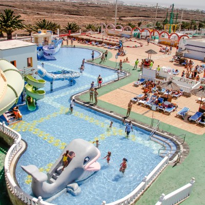 Aerial view of a water park with slides, pools, and people sunbathing.