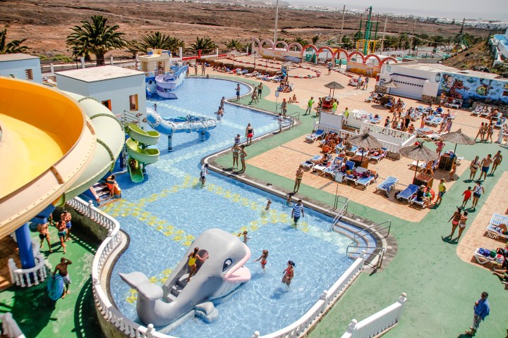 Aerial view of a water park with slides, pools, and people sunbathing.