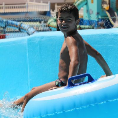 Smiling boy on a blue inflatable ring in a water park.