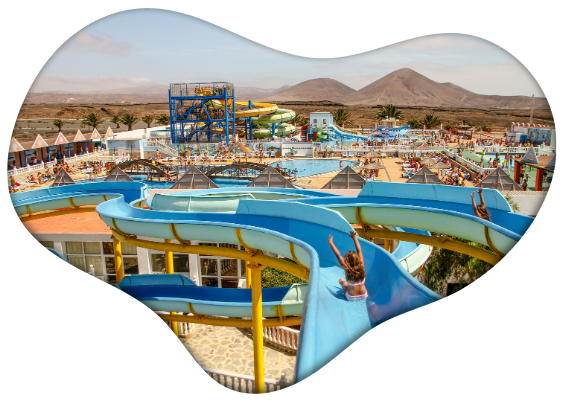 View of a water park with blue slides and a desert landscape in the background.